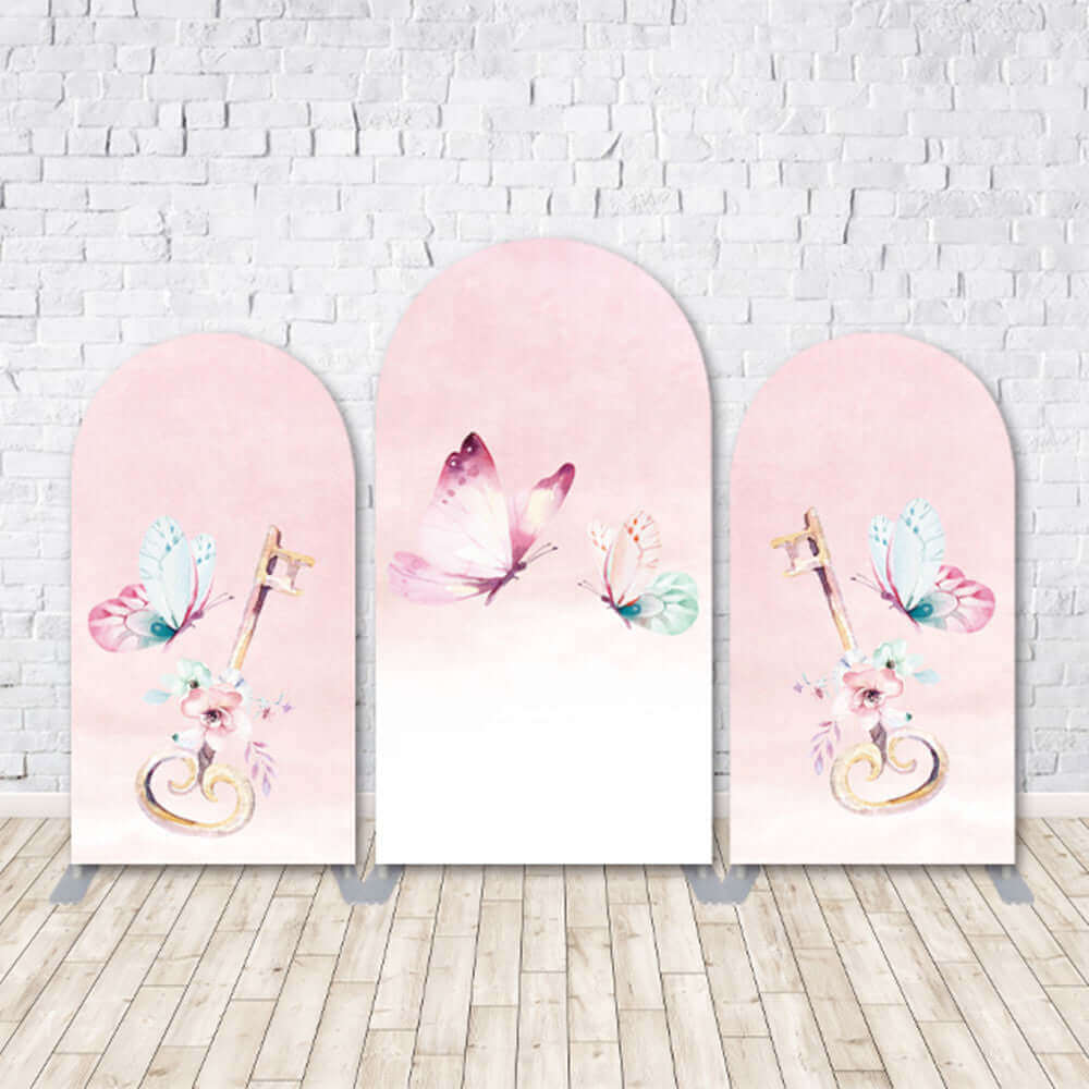 Butterfly-themed arched backdrop set with soft pink pastel tones, featuring elegant butterfly illustrations and golden keys with floral accents, perfect for baby showers, weddings, or birthday events.