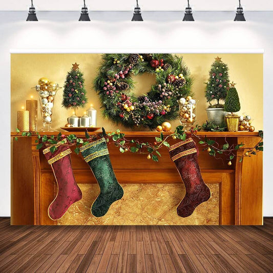 A festive Christmas backdrop featuring a golden mantel with red and green stockings, garlands, ornaments, and a holiday wreath.