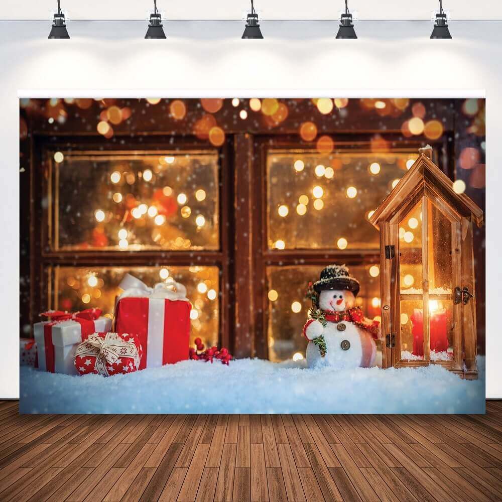 Christmas-themed backdrop featuring a cheerful snowman, glowing wooden lantern, festive red and white gifts, and a snowy windowsill with warm bokeh lights in the background.