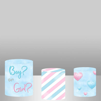 A set of three gender reveal cylinder covers, including one with "Boy or Girl?" text, one with pink and blue stripes, and one with hearts, complementing gender reveal party decor.