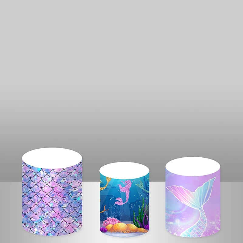 Set of three coordinating cylinder covers including a pastel mermaid scale design, an underwater scene with a mermaid, and a glittering pastel mermaid tail graphic, perfect for enhancing ocean-themed party decor.