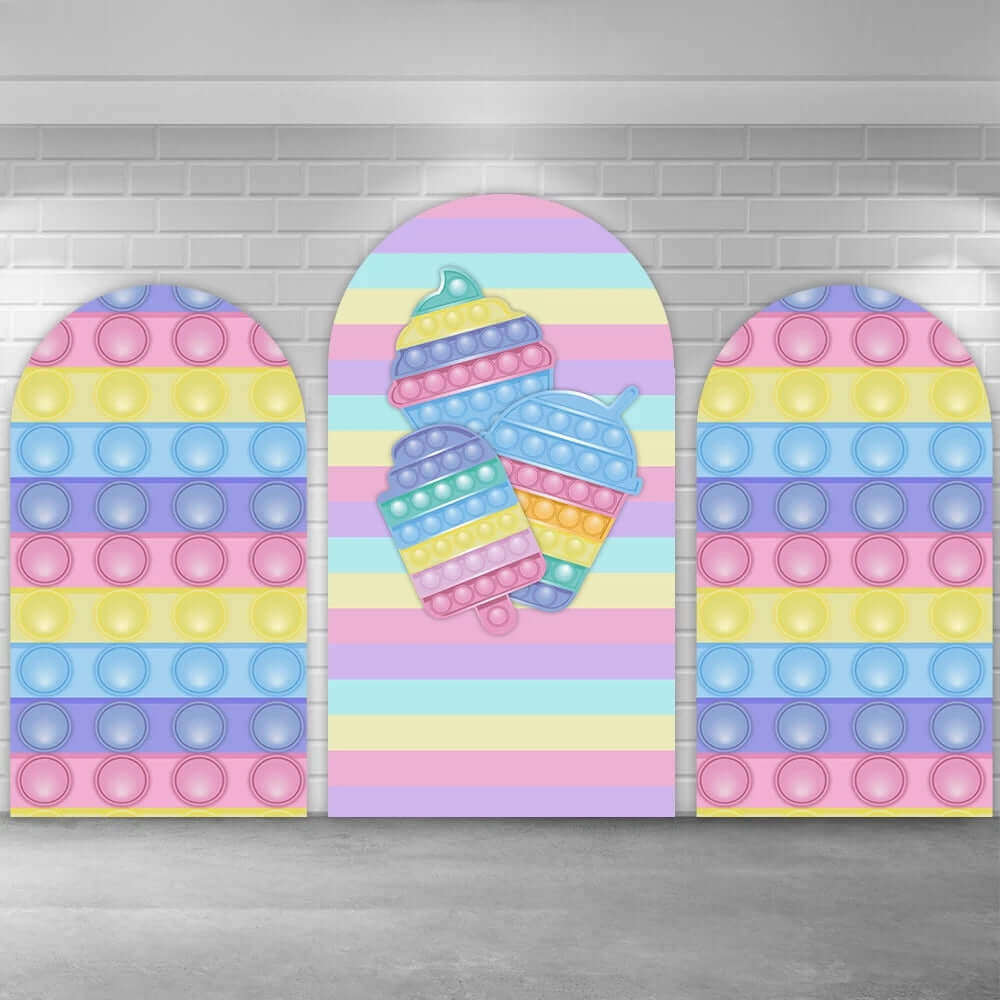 Pop It-themed arched backdrop set with three panels featuring pastel rainbow colors, ice cream Pop It designs in the center, and circular Pop It patterns on the left and right panels.