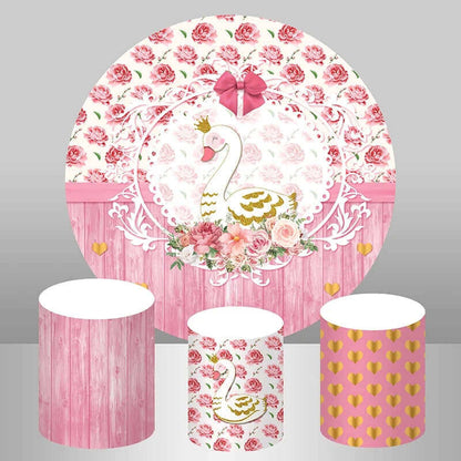 Elegant party decoration set featuring a pink round backdrop with a golden crowned swan surrounded by floral accents, accompanied by three matching cylinder covers.