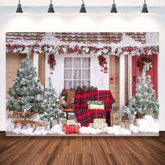 Christmas porch backdrop featuring snow-covered trees, a bench with a red plaid blanket, wrapped gifts, a sleigh, and festive garlands on a snowy porch.