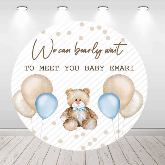 Round baby shower backdrop featuring a teddy bear with blue and beige balloons, elegant text reading 'We Can Bearly Wait to Meet You Baby Emari,' and neutral diagonal stripe background.