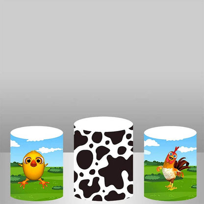 Three farm-themed cylinder covers: one with a chick, one with a black-and-white cow pattern, and one with a rooster in a green field.