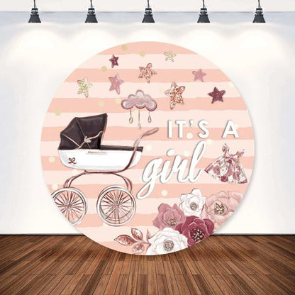 Round baby shower backdrop with soft pink stripes, a vintage baby carriage, glittering rose gold stars, and floral accents. Text reads 'It’s A Girl' in white.