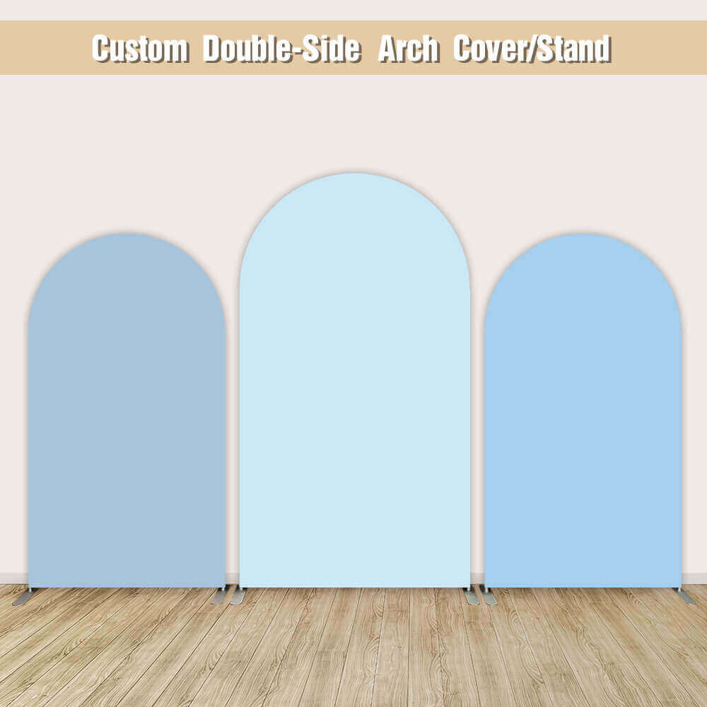 Three-panel light blue arched backdrop covers with smooth fabric design, supported by metal stands on a wooden floor and beige wall background.