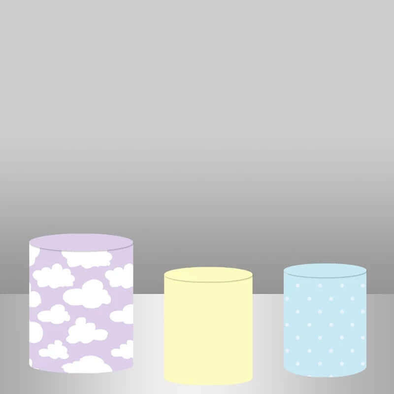 Three plinth covers for kids' party decor: one with white clouds on a purple background, one solid pastel yellow, and one light blue with polka dots.