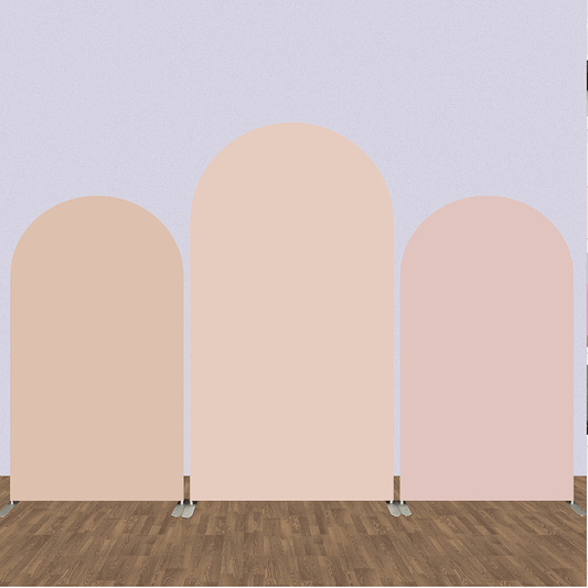 Set of three solid color arched backdrops in soft nude tones of peach, blush pink, and beige, placed on a wooden floor, ideal for minimalist event decor.