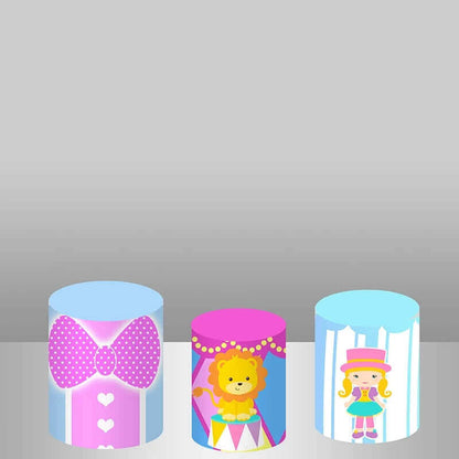 Three colorful cylinder covers with circus designs, including a pink bow, a smiling lion on a podium, and a cartoon girl in a circus costume.