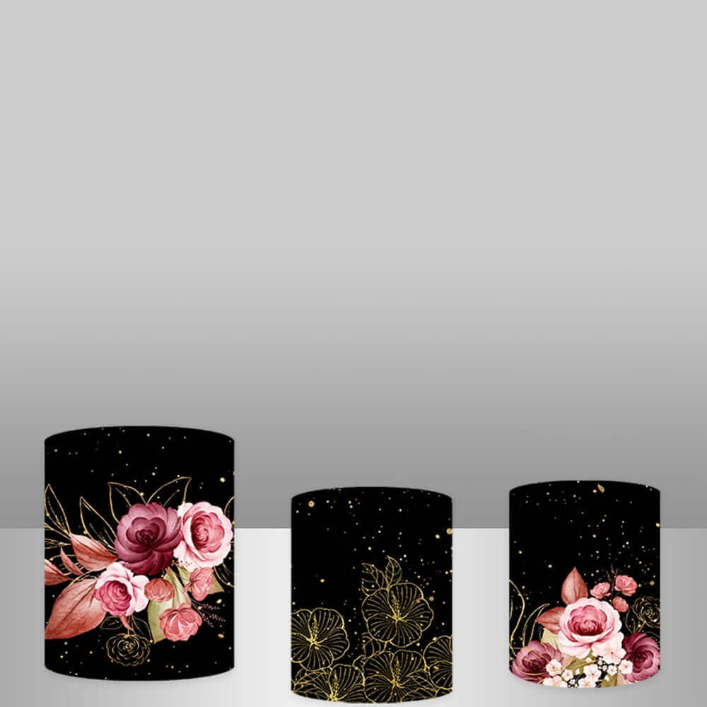 A set of three decorative cylinder covers with black backgrounds, pink roses, and gold accents, ideal for elegant 15th birthday parties or quinceañeras.