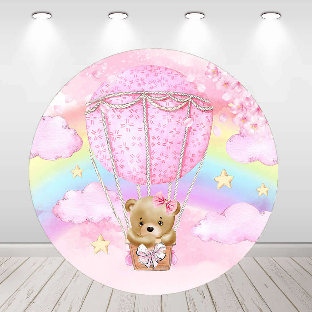 Round backdrop featuring a teddy bear sitting in a pink hot air balloon, surrounded by pastel pink clouds, a rainbow, and golden stars, perfect for baby showers and birthday parties.