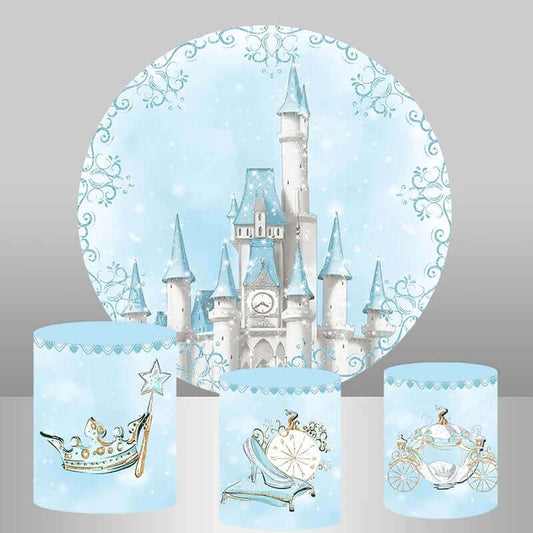 Blue fairytale castle-themed party backdrop with a majestic round backdrop featuring a castle and three matching cylinder covers adorned with a crown, glass slipper, and royal carriage.