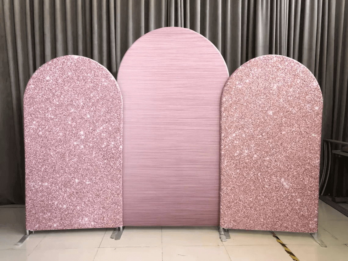 Rose gold glitter and pink arched backdrop set with two glittery panels and one solid pink centerpiece, displayed on metal stands, ideal for elegant events and photoshoots.