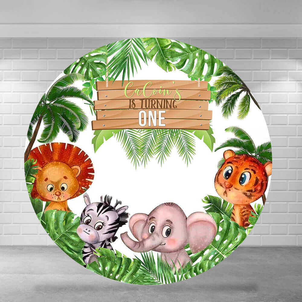 Round safari jungle-themed backdrop featuring a wooden sign reading "CaCoin's is Turning One," with a lion, zebra, elephant, and tiger surrounded by green tropical leaves and palm trees.