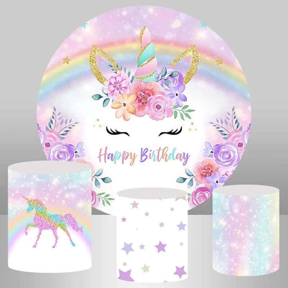 Unicorn-themed birthday party backdrop featuring a golden glitter unicorn horn, pastel rainbow, florals, and "Happy Birthday" text, paired with plinth covers showing a glitter unicorn, star pattern, and pastel glitter design.