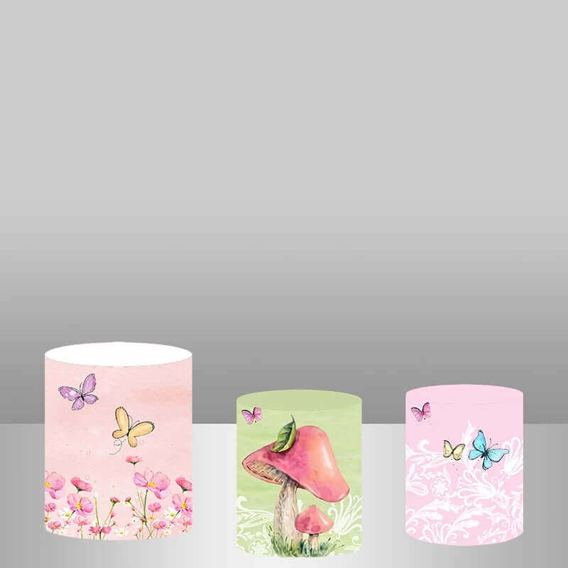 Three fairy-themed plinth covers featuring butterflies and flowers, a pink mushroom design, and a delicate pink floral pattern, perfect for a whimsical party.