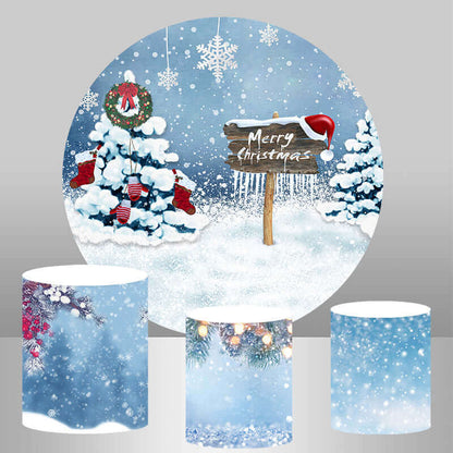 Christmas decoration set with a snowy winter backdrop featuring a rustic 'Merry Christmas' sign, decorated trees, and three coordinating winter-themed cylinder covers.