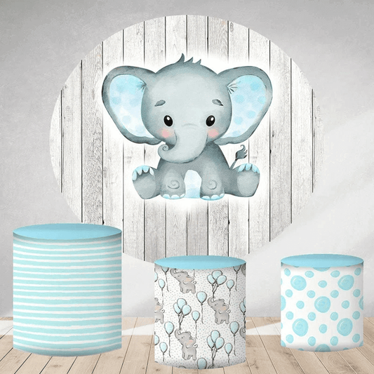 Adorable baby blue elephant round backdrop with rustic grey wood background, paired with three matching cylinder covers in striped, balloon, and polka-dot patterns, perfect for baby showers or birthdays.